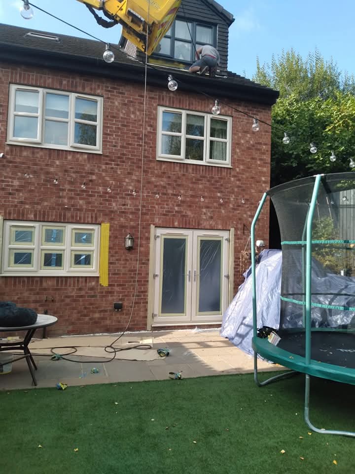 Rear of brick house during uPVC spraying with masked windows, French doors and access equipment
