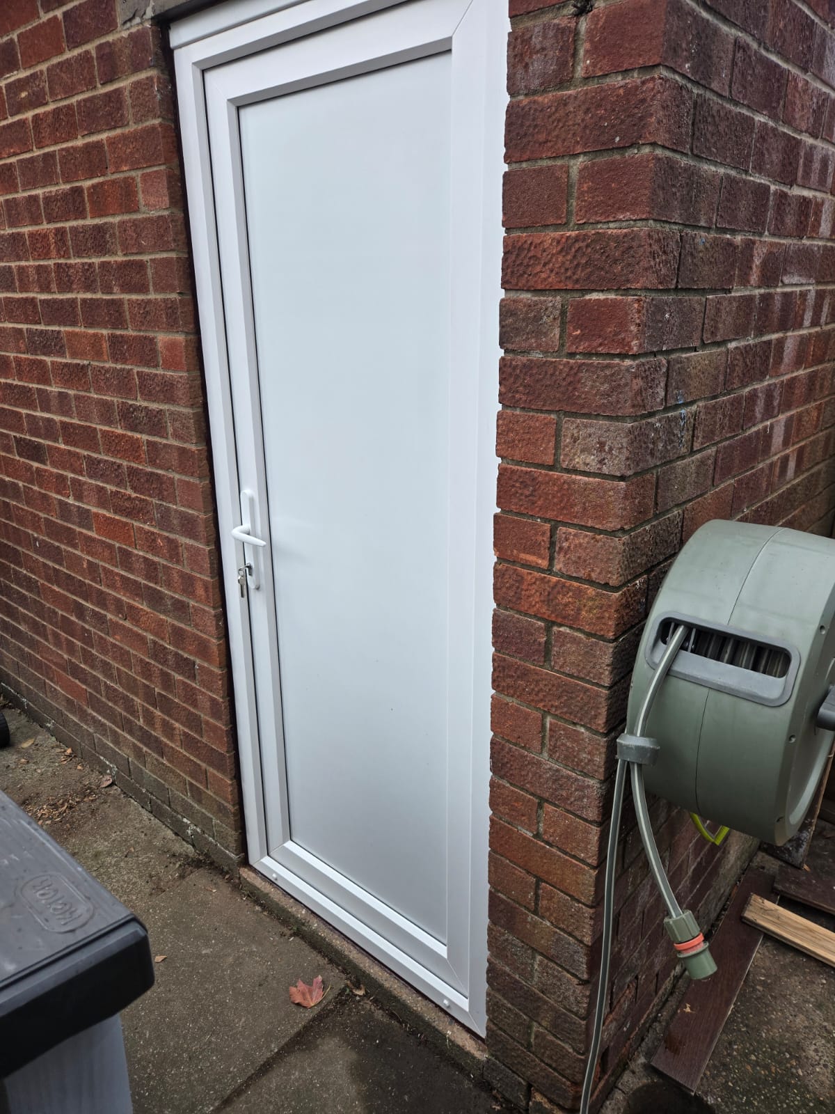 White uPVC side door with solid panel fitted in a red brick outbuilding